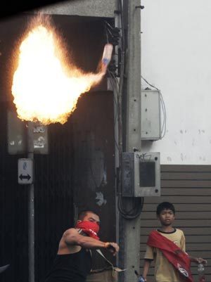 A supporter of ousted Thai prime minister Thaksin Shinawatra hurls a petrol bomb towards riot troops in Bangkok April 13, 2009. The Thai army cracked down on anti-government protesters on Monday, firing warning shots at a major junction in the capital at demonstrators who responded by hurling petrol bombs. [Xinhua/Reuters]