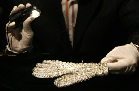 An assistant shines a flashlight on Michael Jackson's white crystal-covered glove in Beverly Hills, California April 13, 2009. Items from the life and career of the pop star will be auctioned from April 22-25.[Xinhua/Reuters]