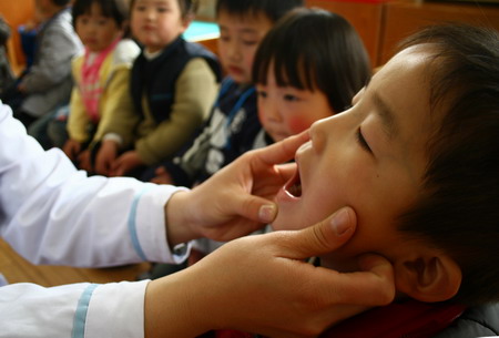 A child has his tongue checked up at the kindergarten in Fuyang, east China's Anhui province, April 10, 2009. [CFP]