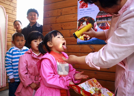 Children have their tongues checked up before stepping into the kindergarten in Beijing, April 10, 2009. [CFP]