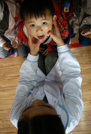 A child has his tongue checked up at the kindergarten in Fuyang, east China's Anhui province, April 10, 2009. [CFP]