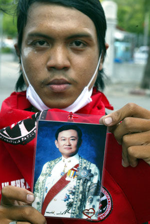 An anti-government protestor displays a photo of former Thai Prime Minister Thaksin Shinawatra during a rally at the Government House in Bangkok, capital of Thailand, April 13, 2009. Anti-government protestors have set up several blocks to control the people who wanted to enter the site of the rally. 