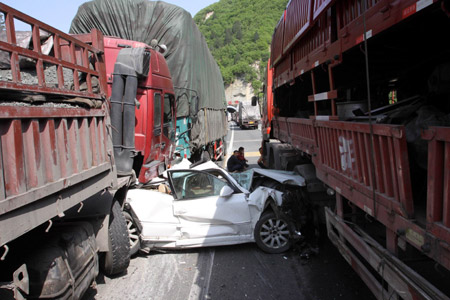 Photo taken on April 14, 2009 shows a car squeezed between trucks on the Xishang Expressway in northwest China's Shaanxi Province. Four accidents occurred continuously within a two-kilometer section of the Xishang Expressway on Tuesday morning, causing two people seriously injured and 16 vehicles damaged. [Wu Anbiao/Xinhua] 