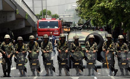 Thai army soldiers block the road junction outside the Government House in Bangkok, capital of Thailand, April 14, 2009. Thai anti-government protesters began to head home Tuesday afternoon after their leaders surrendered to police and called an end to the rally. But the security in the capital Bangkok is still tight. [Zhang Fengguo/Xinhua]