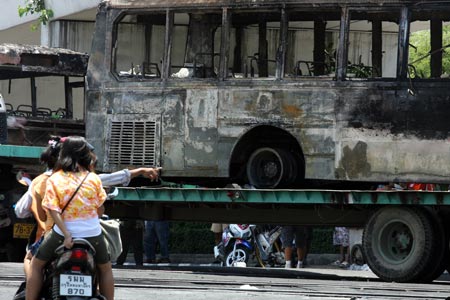 A rider points at the damaged vehicles near the Government House in Bangkok, capital of Thailand, April 14, 2009. Thai anti-government protesters began to head home Tuesday afternoon after their leaders surrendered to police and called an end to the rally. But the security in the capital Bangkok is still tight. [Zhang Fengguo/Xinhua]