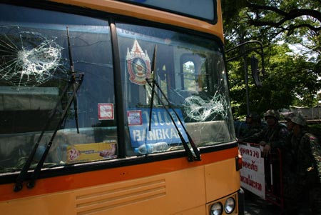 Thai soldiers stand next to a damaged vehicle near the Government House in Bangkok, capital of Thailand, April 14, 2009. Thai anti-government protesters began to head home Tuesday afternoon after their leaders surrendered to police and called an end to the rally. But the security in the capital Bangkok is still tight. [Zhang Fengguo/Xinhua]