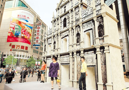 Shanghai locals pose for a photograph on Wednesday at the Nanjing Road Pedestrian Mall, where a model of the Ruins of St. Paul, one of Macao's landmark scenic spots, was set up to prepare for 'Macao Week in Shanghai,' which begins on Thursday. The event is to celebrate the 10th anniversary of the establishment of the Macao Special Administrative Region on December 20, 1999. [Photo: Shanghai Daily]