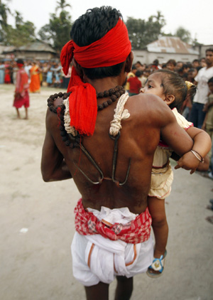 A Hindu devotee with his back pierced carries a child during the 'Chadak' ritual in the eastern Indian city of Siliguri April 14, 2009. Hundreds of Hindu devotees attend the ritual, held to worship the Hindu deity of destruction Lord Shiva, on the last day of the Bengali calendar year. [Xinhua/Reuters]