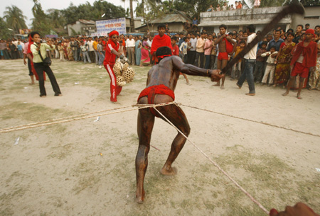 Hindu devotee displays a feat of strength by pulling people along during the 'Chadak' ritual in the eastern Indian city of Siliguri April 14, 2009. Hundreds of Hindu devotees attend the ritual, held to worship the Hindu deity of destruction Lord Shiva, on the last day of the Bengali calendar year. [Xinhua/Reuters]