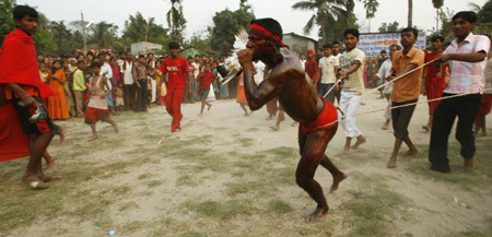 A Hindu devotee eats a live pigeon as he displays a feat of strength by pulling people along during the 'Chadak' ritual in the eastern Indian city of Siliguri April 14, 2009. [Xinhua/Reuters] 