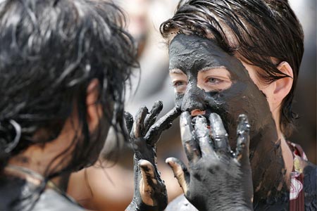 Tourists cover their bodies with mud on Jordan's side of the Dead Sea, the lowest point on earth, April 15, 2009. A growing number of medical patients and visitors are flocking toward Jordan's Dead Sea for its black mud which is known to have healing properties that can treat skin diseases. [Xinhua/Reuters]