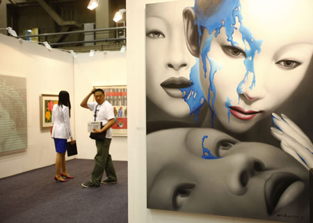 Visitors look at paintings in the opening day of the China International Gallery Exposition (CIGE) 2009 in Beijing April 15, 2009. The fair showcases over 80 selected galleries and presents some 5,000 pieces of art projects including painting, sculptures, multimedia creations.[Li Mingfang/Xinhua]