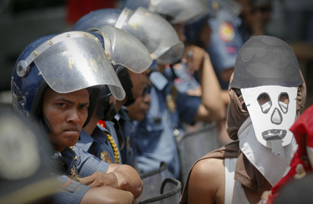 Philippine police block protesters against the Philippines-US Visiting Forces Agreement (VFA) in Manila, the Philippines, on April 16, 2009. Protesters called for the abolition of the VFA, which allows the presence of US troops in the country to conduct military exercises with Filipino counterparts in various Philippine provinces. [Luis Liwanag/Xinhua]