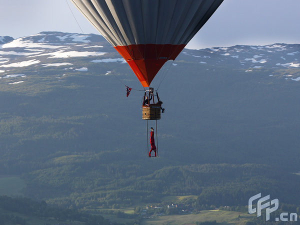 Eskil Ronningsbakken balancing on a trapeze below a hot air balloon above Voss in Norway. [Barcroftmedia/CFP]