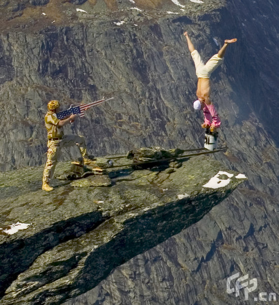 Eskil Ronningsbakken balancing on the side of a cliff in Norway as a man points a fake gun at him. This picture was taken as part of an advertising campaign for the Norwegian police about risk taking. [Barcroftmedia/CFP]