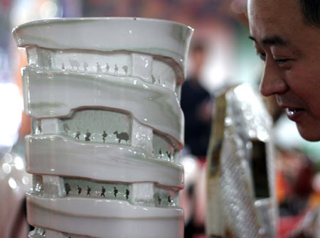 An exhibitor from Jiaozuo City displays a porcelain article at Henan Tourist Commodities Exposition in Sanmenxia, a city of central China's Henan Province, April 16, 2009. About 600 companies participated in the exposition with over 2,000 types of commodities on show including Luoyang Tri-colored Pottery of Tang Dynasty, Embroidery of ancient Kaifeng, etc.[Xinhua/Zhang Xiaoli]