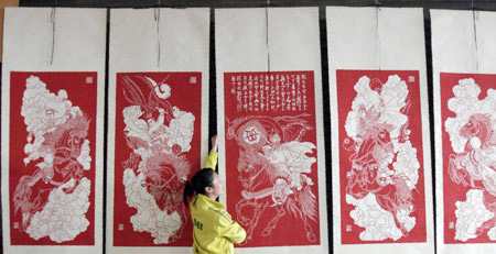  An exhibitor displays a series of paper-cuts on the title of 'Biography of Yuefei' at Henan Tourist Commodities Exposition in Sanmenxia, a city of central China's Henan Province, April 16, 2009. About 600 companies participated in the exposition with over 2,000 types of commodities on show including Luoyang Tri-colored Pottery of Tang Dynasty, embroidery of ancient Kaifeng, etc. [Xinhua/Zhang Xiaoli]