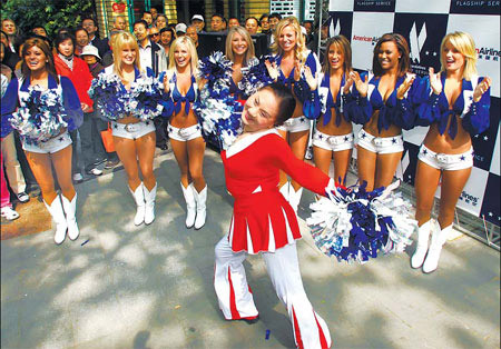 Sixty-seven-year-old Wang Guoyu, a hua-gu (flower drum) dancer from Shanghai, exchanges dancing tips with America's Sweethearts, one of the most famous cheerleading troupes from the US, at the city's Xiangyang Park on Friday. [Photo: Chinadaily.com.cn]