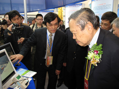 Yang Chen-Ning (R) listens carefully with the illustrations of the high-tech achievements exhibited. [Photo: CRIENGLISH.com]