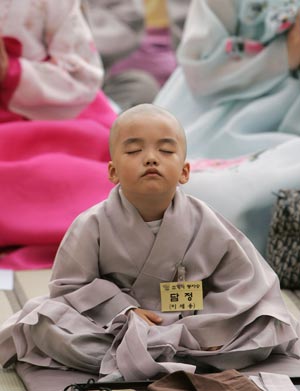 Novice monk Dam Jung dozes after a Buddhist monk cut his hair during a ceremony at the Jogye temple in Seoul April 19, 2009. A group of nine boys entered the temple to experience life as monks for 18 days, ahead of celebrations for Buddha's birth date on May 2. [Xinhua/Reuters]