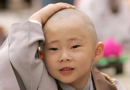  A novice monk strokes his head after a Buddhist monk cut his hair during a ceremony at the Jogye temple in Seoul April 19, 2009. A group of 9 boys entered the temple to experience life as monks for 18 days, ahead of celebrations for Buddha's birth date on May 2. [Xinhua/Reuters] 