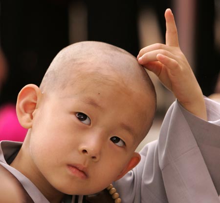 A novice monk strokes his head after a Buddhist monk cut his hair during a ceremony at the Jogye temple in Seoul April 19, 2009. A group of nine boys entered the temple to experience life as monks for 18 days, ahead of celebrations for Buddha's birth date on May 2. [Xinhua/Reuters]