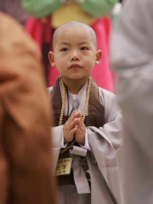 Novice monk Myo Sung takes part in a ceremony after a Buddhist monk cut his hair at the Jogye temple in Seoul April 19, 2009. A group of 9 boys entered the temple to experience life as monks for 18 days, ahead of celebrations for Buddha's birth date on May 2. [Xinhua/Reuters]