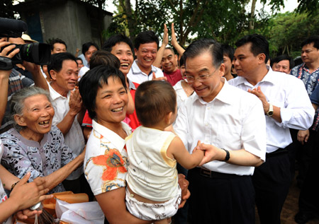 Chinese Premier Wen Jiabao (Front, R) holds a baby's hand during a visit to Benli village in Haikou, south China's Hainan Province April 19, 2009. Wen was on an inspection tour on the island province from April 18 to 19. [Huang Jingwen/Xinhua] 