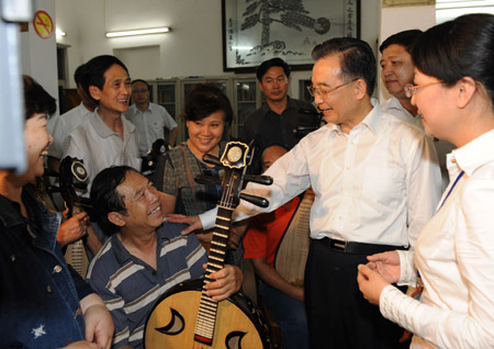 Chinese Premier Wen Jiabao (3rd, R) talks with a resident playing a folk instrument at a residential community in Haikou, south China's Hainan Province, April 18, 2009. [Huang Jingwen/Xinhua] 