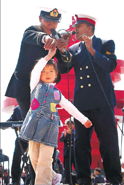 Su Qinglei, 3, dances with a Bangladeshi naval officer attending celebrations marking the 60th anniversary of the founding of the People's Liberation Army Navy in Qingdao, Shandong province, yesterday. Zhang Lei