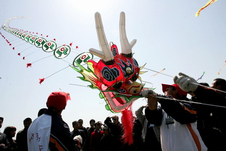 Team members prepare to fly a giant kite in the shape of a dragon at the 26th Weifang International Kite Festival in Weifang, east China's Shandong Province, on Tuesday, April 21, 2009. Weifang, the birth place of kites, holds the international kite festival every year in spring since 1984, attracting competitors and tourists worldwide. [Photo: CFP]
