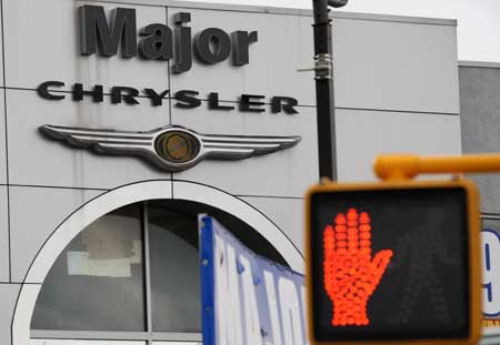 A walking stop sign is seen in front of the logo of Chrysler at a car dealership in New York, the United States, April 7, 2009. The U.S. Treasury will provide a further five billion dollars in loans to General Motors and 500 million dollars to Chrysler as the automakers work on their viability plans, officials said Tuesday. [Xinhua]