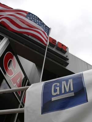  File photo taken on April 7, 2009 shows a US national flag flaunting above the logo of General Motors at a car dealership in New York, the United States. The U.S. Treasury will provide a further five billion dollars in loans to General Motors and 500 million dollars to Chrysler as the automakers work on their viability plans, officials said Tuesday. [Liu Xin/Xinhua]