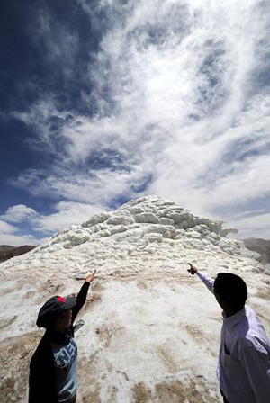 Two visitors watch the wonder of geothermal seracs at the foot of Mt. Nyainqentanglha, 150 km from Lhasa, capital of southwest China's Tibet, on April 20, 2009. There, a spewing geothermal fountain has been frozen throughout winter, forming a marvellous view of geothermal seracs. Many tourists are attracted to visit it. [Chogo/Xinhua]　