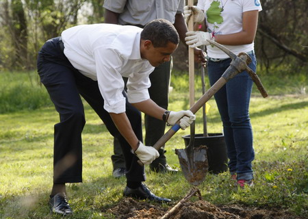 US President Barack Obama digs a hole to plant an Earth Day tree at Kenilworth Aquatic Gardens in Washington, April 21, 2009. [China Daily/Agencies]