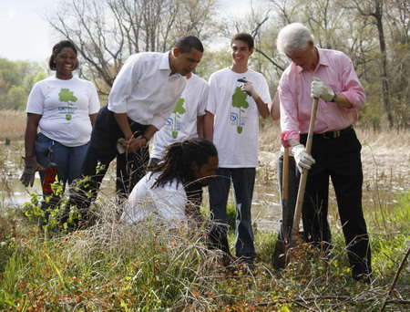 US President Barack Obama (2nd L) watches as former President Bill Clinton (R) plants a Earth Day tree at Kenilworth Aquatic Gardens in Washington, April 21, 2009. [China Daily/Agencies] 