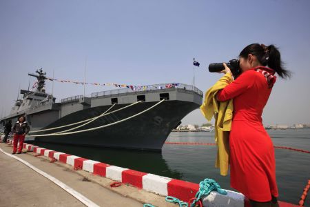 A woman takes photographs of the 'Dokdo' amphibious assault ship from the Republic of Korea in Qingdao, east China's Shandong Province, April 22, 2009. Part of foreign naval vessels which came to attend the 60th anniversary celebration of Chinese People's Liberation Army Navy was open to public on Wednesday, attracting lots of visitors. [Zha Chunming/Xinhua]