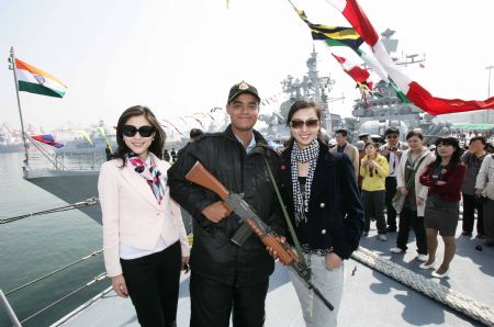 Two local women pose for photos with a navy soldier as they visit the 'Mumbai' missile destroyer of India in Qingdao, east China's Shandong Province, April 22, 2009. Part of foreign naval vessels which came to attend the 60th anniversary celebration of Chinese People's Liberation Army Navy were open to public on Wednesday, attracting lots of visitors. [Zha Chunming/Xinhua]