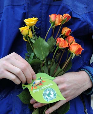 A volunteer of the U.S.-based conservation group Rainforest Alliance holds flowers and a card written 'shop sustainbaly' at the Union Sqaure in New York, the United States, April 22, 2009. Volunteers here on Wednesday distributed flower seeds and cards with tips about environment protection to passersby to mark the annual Earth Day. [Shen Hong/Xinhua]