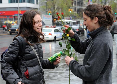 A volunteer (R) of the U.S.-based conservation group Rainforest Alliance sends flowers to a pedestrian at the Union Square in New York, the United States, April 22, 2009. Volunteers here on Wednesday distributed flower seeds and cards with tips about environment protection to passersby to mark the annual Earth Day. [Shen Hong/Xinhua]