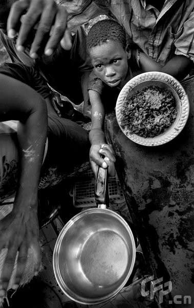 Clayson Menthor, 13, holds out a small pot for some beans and rice provided by a church outside of Cabaret, Haiti, September 9, 2008. [CFP]