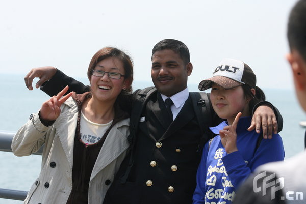 Two girls pose with a marine in Qingdao, east China's Shandong Province, April 22, 2009. Part of foreign naval vessels which came to attend the 60th anniversary celebration of Chinese People's Liberation Army Navy was open to public on Wednesday, attracting lots of visitors. [CFP]