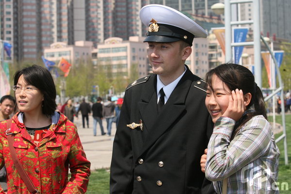 A girl poses with a marine in Qingdao, east China's Shandong Province, April 22, 2009. Part of foreign naval vessels which came to attend the 60th anniversary celebration of Chinese People's Liberation Army Navy was open to public on Wednesday, attracting lots of visitors. [CFP]