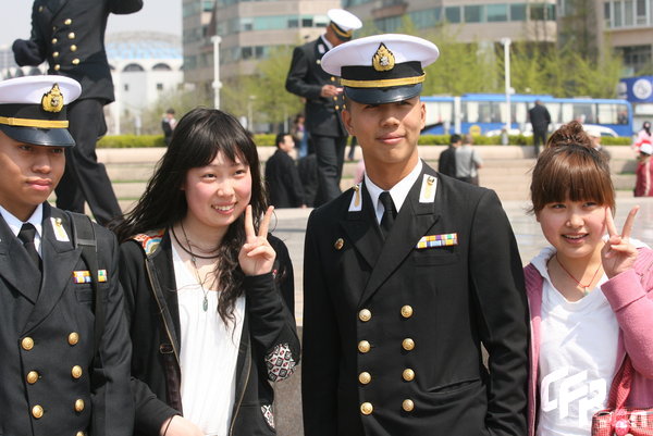 Two girls pose with marines in Qingdao, east China's Shandong Province, April 22, 2009. Part of foreign naval vessels which came to attend the 60th anniversary celebration of Chinese People's Liberation Army Navy was open to public on Wednesday, attracting lots of visitors. [CFP]