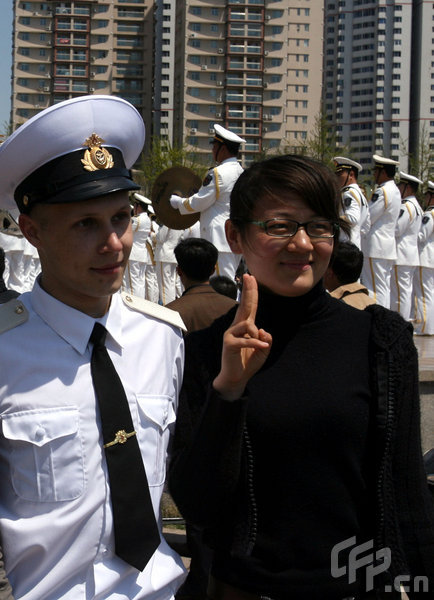 A girl poses with a marine in Qingdao, east China's Shandong Province, April 22, 2009. Part of foreign naval vessels which came to attend the 60th anniversary celebration of Chinese People's Liberation Army Navy was open to public on Wednesday, attracting lots of visitors. [CFP]