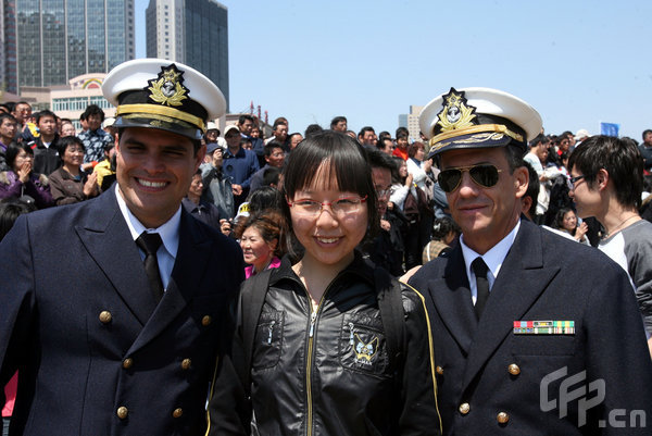 A girl poses with marines in Qingdao, east China's Shandong Province, April 22, 2009. Part of foreign naval vessels which came to attend the 60th anniversary celebration of Chinese People's Liberation Army Navy was open to public on Wednesday, attracting lots of visitors. [CFP]