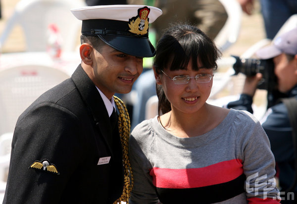 A girl poses with a marine in Qingdao, east China's Shandong Province, April 22, 2009. Part of foreign naval vessels which came to attend the 60th anniversary celebration of Chinese People's Liberation Army Navy was open to public on Wednesday, attracting lots of visitors. [CFP]