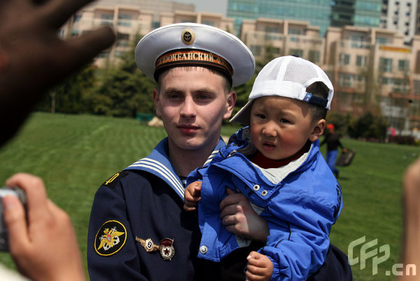 A marines holding a little boy takes photo in Qingdao, east China's Shandong Province, April 22, 2009. Part of foreign naval vessels which came to attend the 60th anniversary celebration of Chinese People's Liberation Army Navy was open to public on Wednesday, attracting lots of visitors. [CFP]