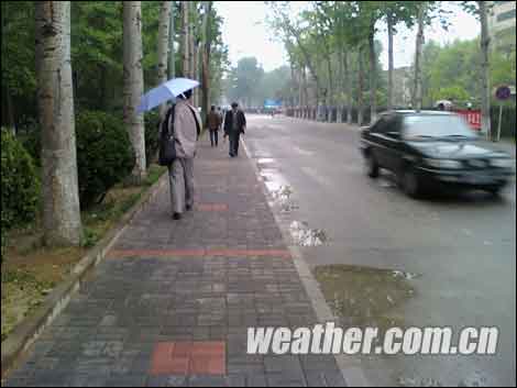 People walk in the rain in Beijing on the morning of April 23, 2009. Influenced by the cold and humid airflow heading south, the capital is enjoying welcome rain after a prolonged spell of drought, according to www.weather.com.cn. 