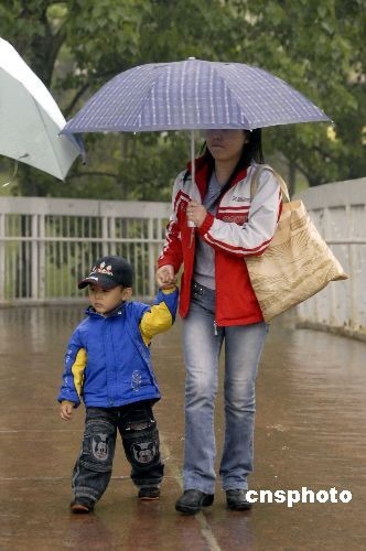 People walk in the rain in Beijing on the morning of April 23, 2009. Influenced by the cold and humid airflow heading south, the capital is enjoying welcome rain after a prolonged spell of drought, according to www.weather.com.cn.